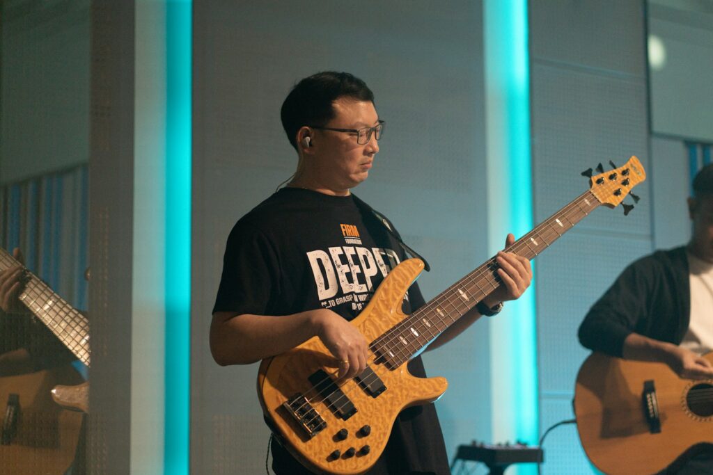 A man plays a bass guitar with another musician